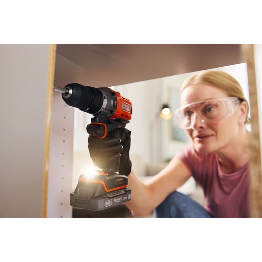 Photo of BLACKDECKER BCD383D1 cordless drill in use, person assembling furniture indoors.