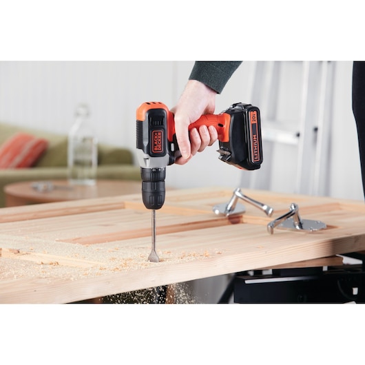 BLACK+DECKER BCD702C1 cordless drill in use on wood, close-up photography.