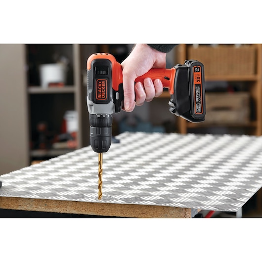 BLACKDECKER BCD702C1 cordless drill in use drilling metal sheet, close-up view, power tool category.
