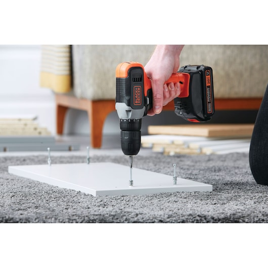 Photo of BLACKDECKER cordless drill BCD702C1 driving screws into a white board on a carpet.