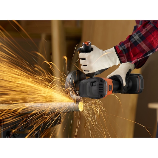 Photo of BLACKDECKER BCG6L8B angle grinder cutting metal pipe, sparks flying, worker wearing gloves.