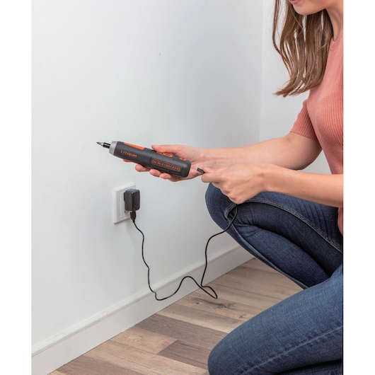Photo of BLACKDECKER BD40K27 cordless screwdriver being charged by a person at a wall outlet.
