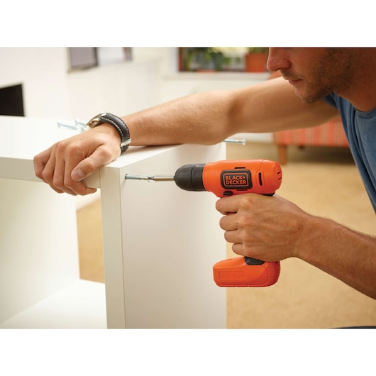 Photo of BLACK+DECKER BDCD8HDPK cordless drill being used to assemble white furniture indoors.