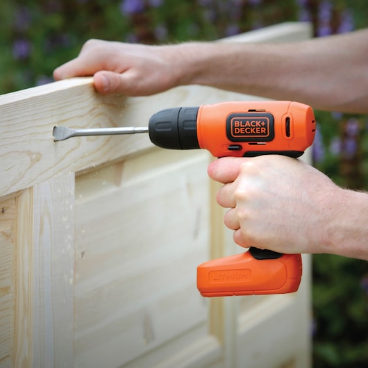 Photo of BLACK+DECKER BDCD8HDPK orange cordless drill in use, drilling into light wood.