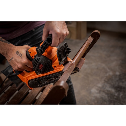 BLACKDECKER BEBS0900 belt sander used on wooden furniture, close-up photography.