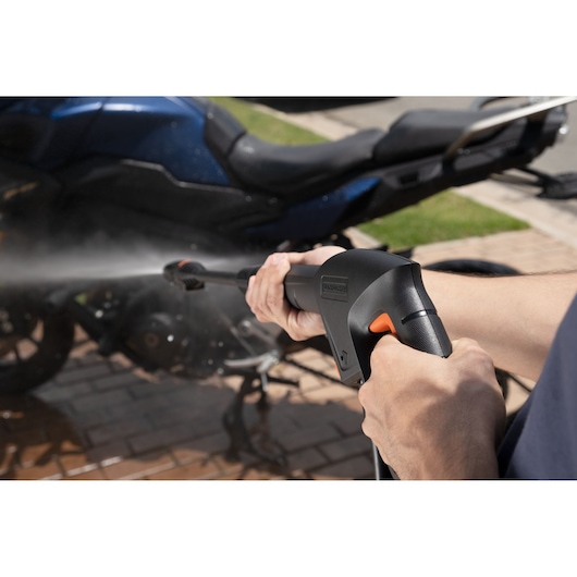 BLACKDECKER BEPW1300 pressure washer being used outdoors to clean a motorcycle.