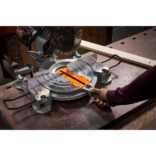BLACKDECKER BES7101800MS miter saw on workbench, side angle, person adjusting handle.