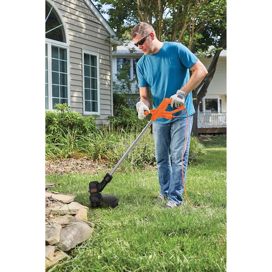 Photo of BLACKDECKER BEST935 string trimmer used for edging grass near stone border in a yard.