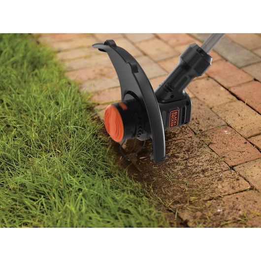 Photo of BLACKDECKER BEST935 string trimmer edging between grass and brick walkway.