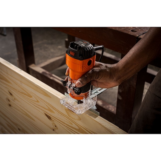 Photo of BLACKDECKER BETR0500 compact router in use, trimming the edge of a light wood board.