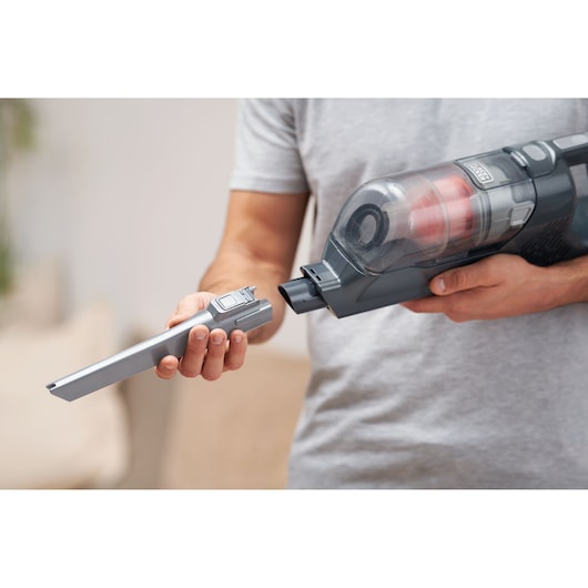 Photo of BLACKDECKER BHFEA18D1 cordless vacuum cleaner held by person, attaching a narrow crevice tool.