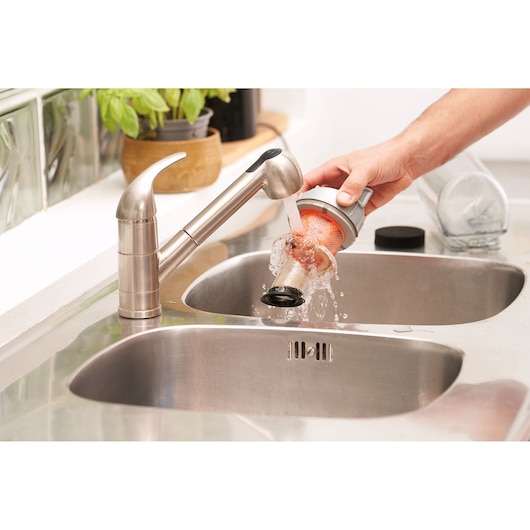 BLACKDECKER BHFEA18D1 vacuum filter being rinsed under faucet in kitchen sink.
