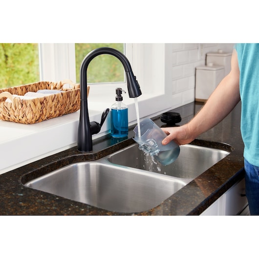 BLACKDECKER BHFEB520D1 kitchen faucet in matte black with curved spout, water running into a glass at sink.